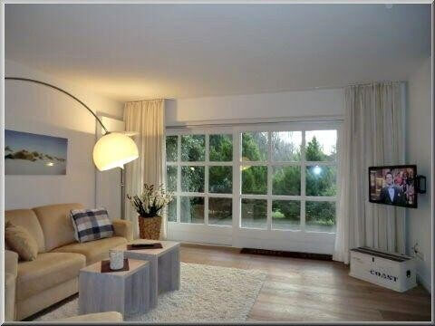 Blick in das helle Wohnzimmer mit Terrassenausgang und Flat-TV