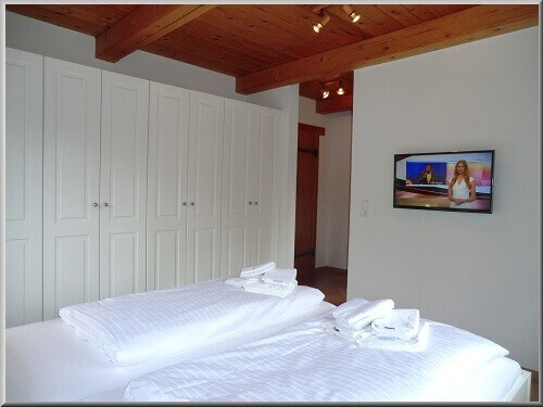 Weiterer Schlafzimmerbereich mit Flat-TV und großem Einbauschrank