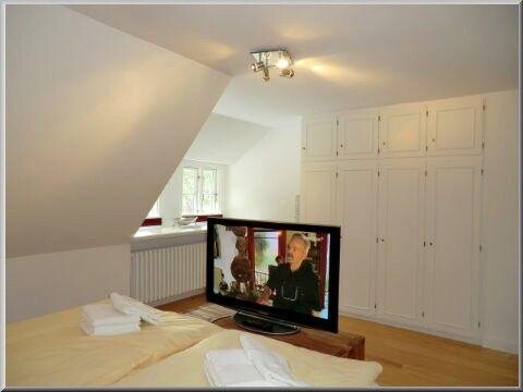 Blick über den großen Flat-TV im Schlafzimmer zum Wandschrank